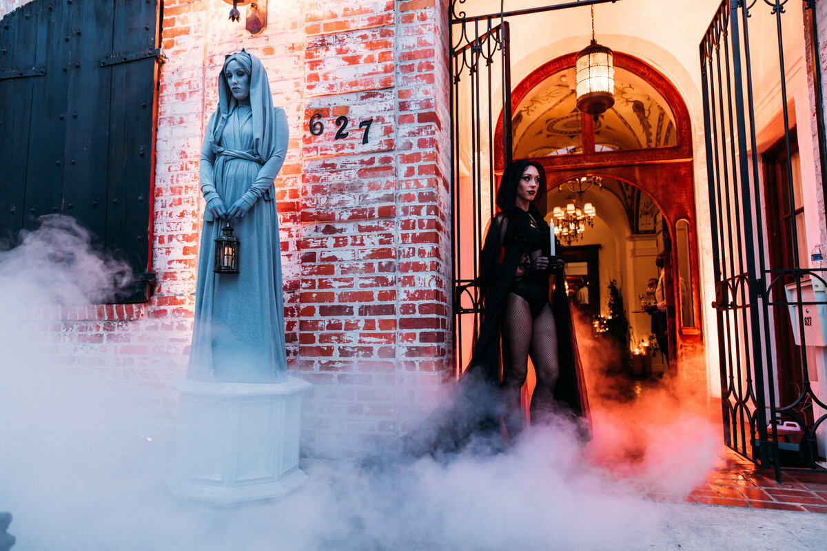 Immersive halloween wedding statues stand at the entrance to carondelet house. Smoke billows around them like a haunted graveyard.