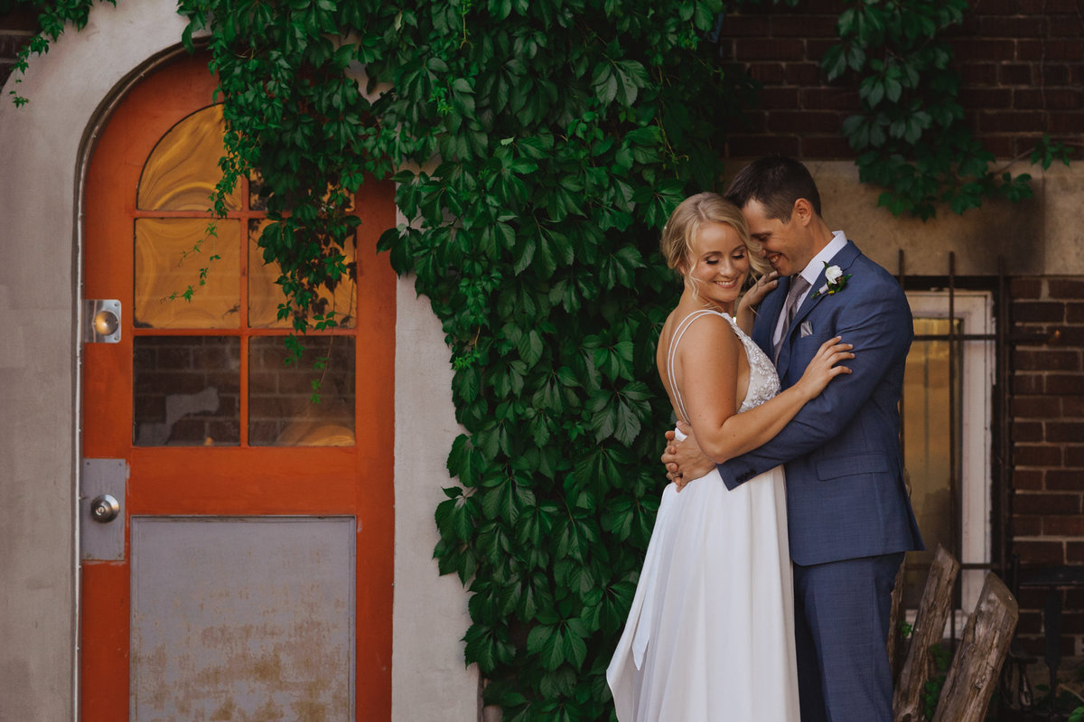 bride and groom standing next to orange door