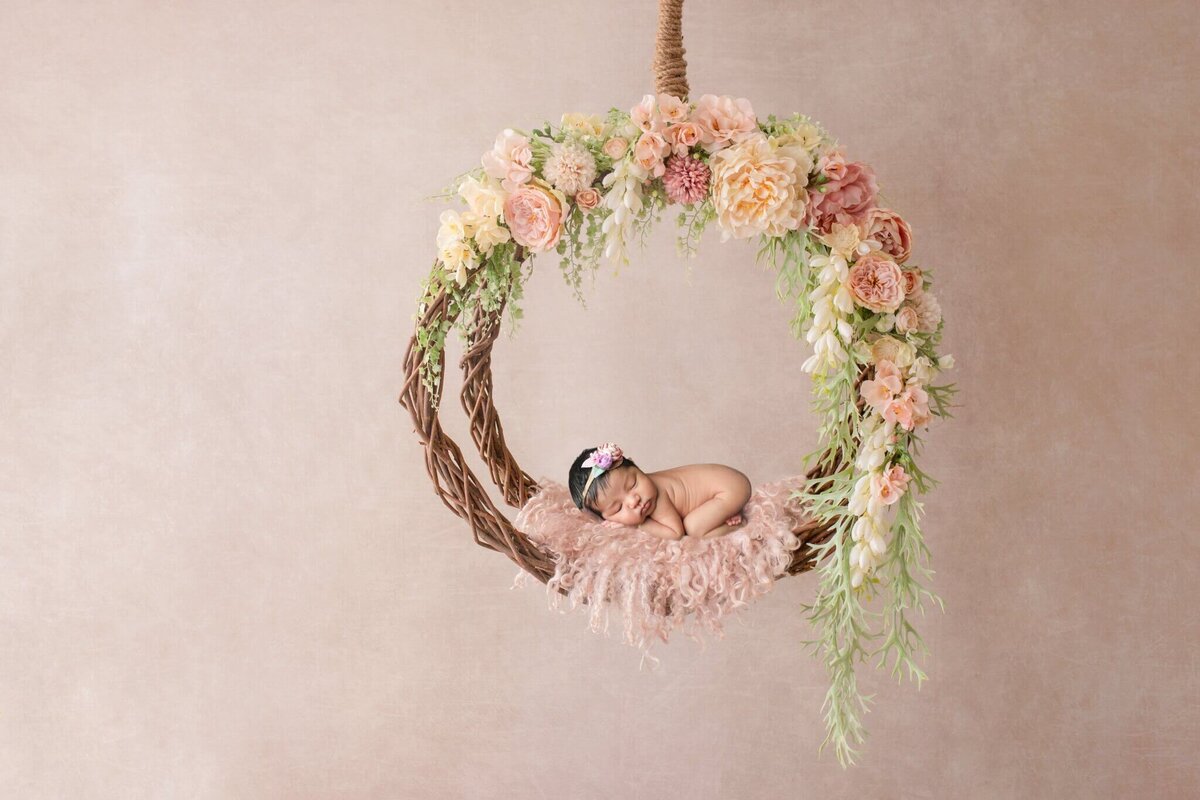 Newborn baby girl sleeping in  floral hoop swing