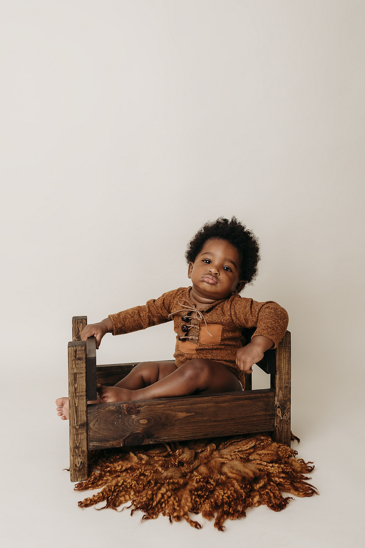 baby sitting in a wooden crib