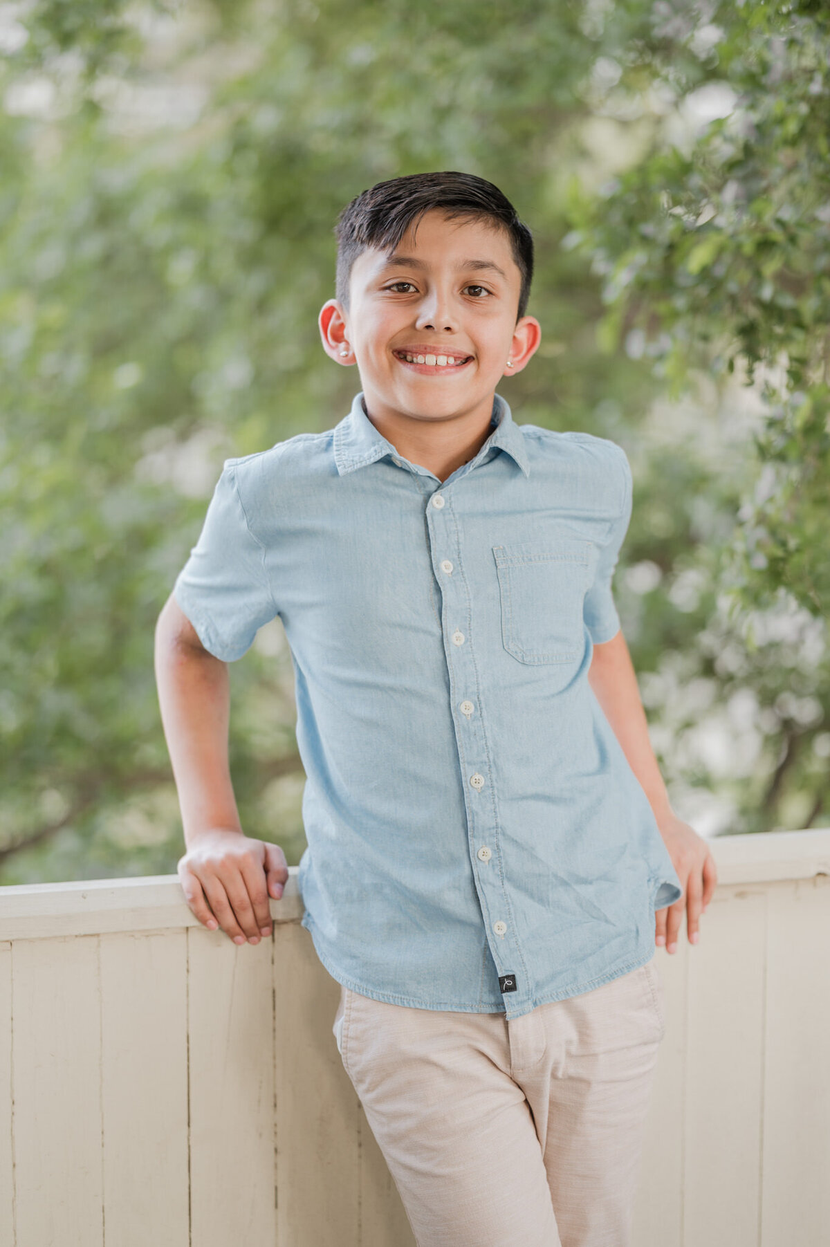 Boy leans against railing and smiles for the camera.