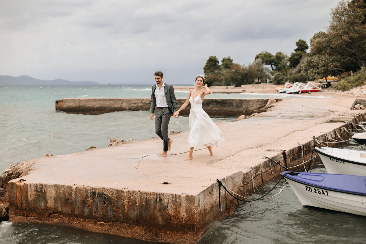 Brautpaar läuft auf einem Steg am Meer in Kroatien