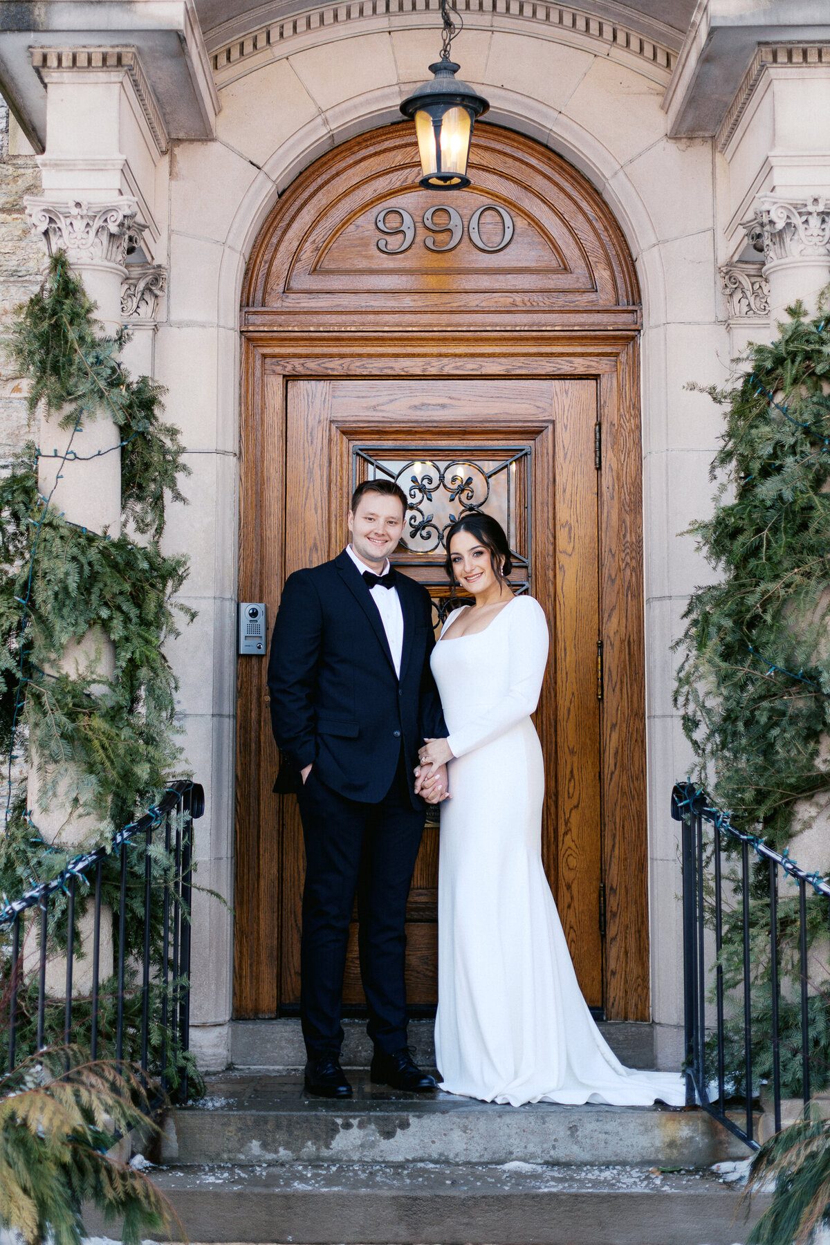 Bride and groom holding hands smiling by the old clasic door at St Paul College Club