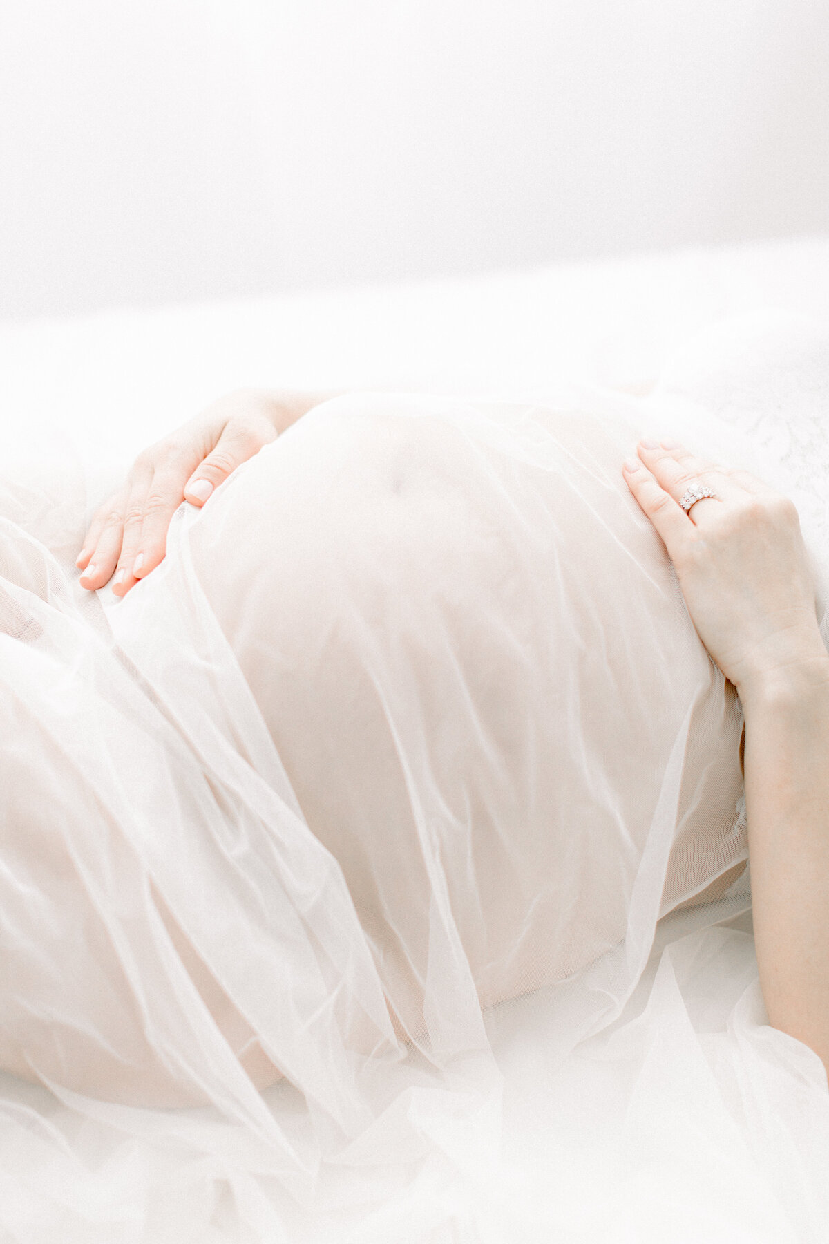 Portrait of expecting mothers belly with tulle draped over