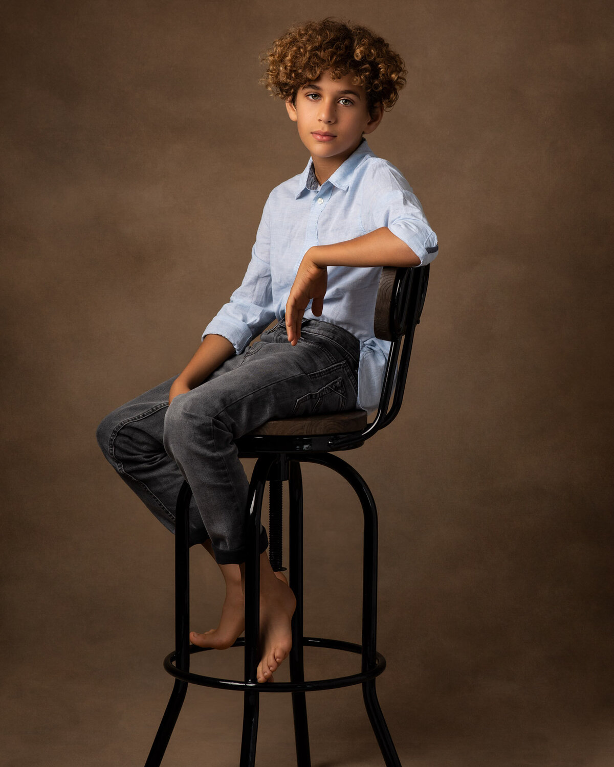 Relaxed sitting boy's portrait leaning on the back of the chair