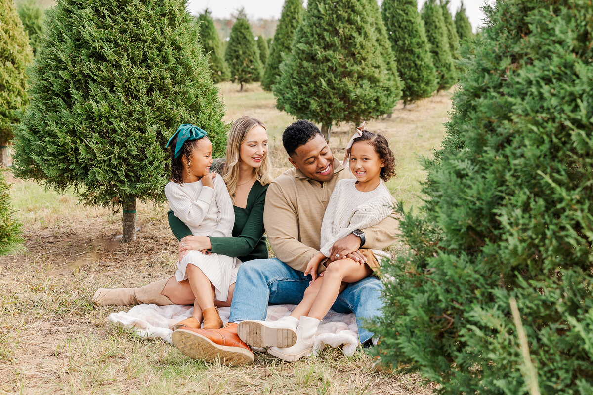 Small girls on rug at a tree farm with red bows in their hair