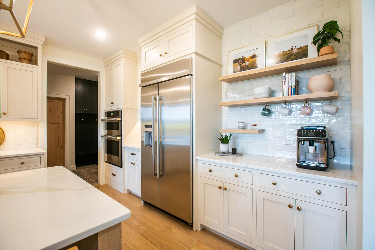 Open kitchen with white cabinets, large island, and quartz countertops in an Otsego custom home