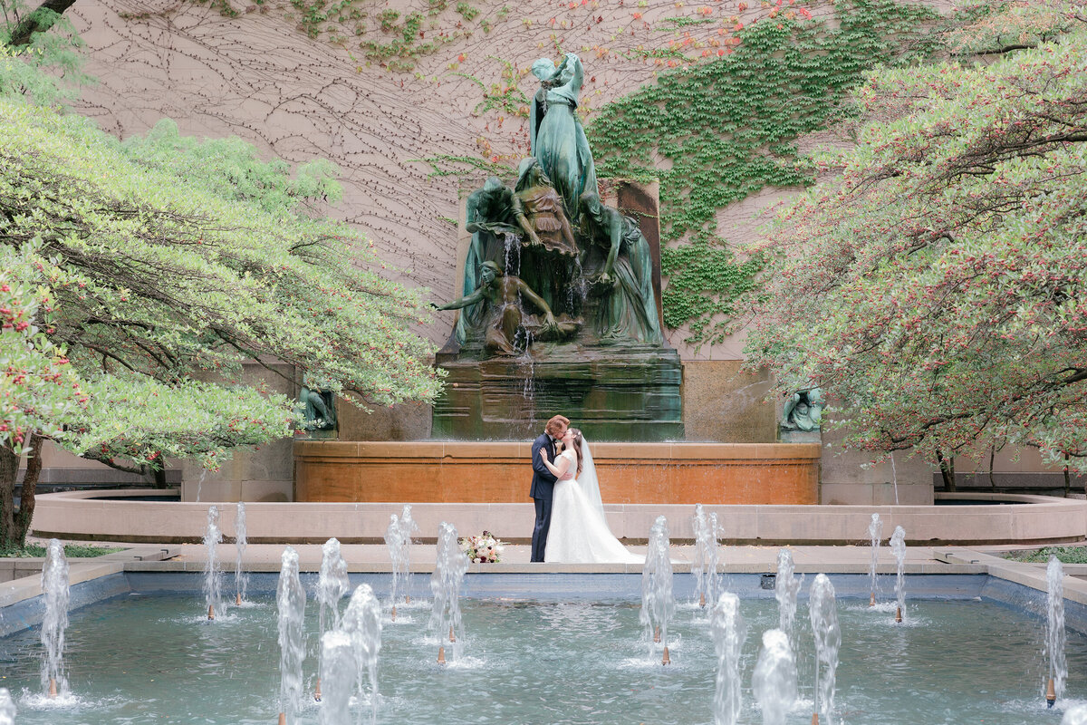 couple kiss in the gardens of the Art institute of Chicago by the fountain 