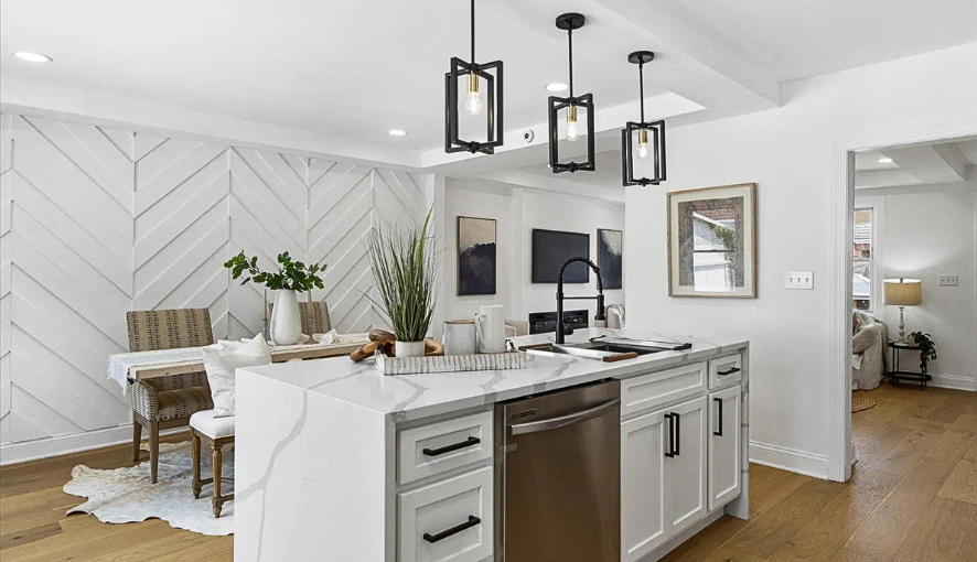 Modern kitchen remodel with quartz waterfall island, custom shaker cabinets, bold pendant lighting, and open flow into the dining and living areas—showcasing craftsmanship and contemporary design.