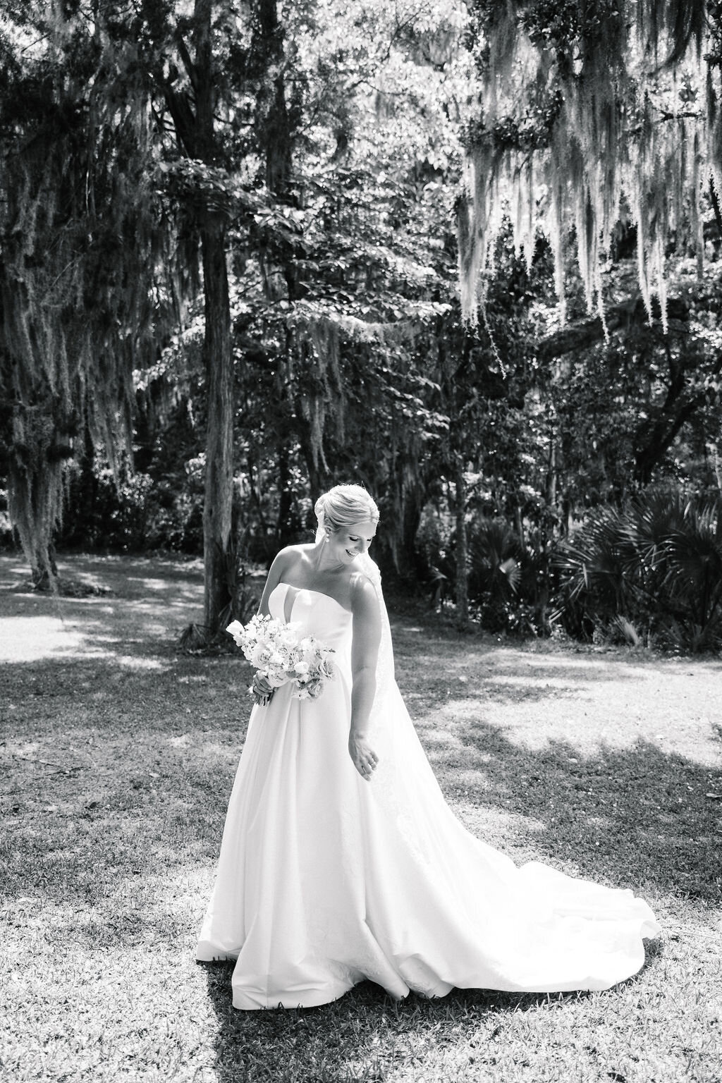 Black and white of bride posing underneath a mossy tree
