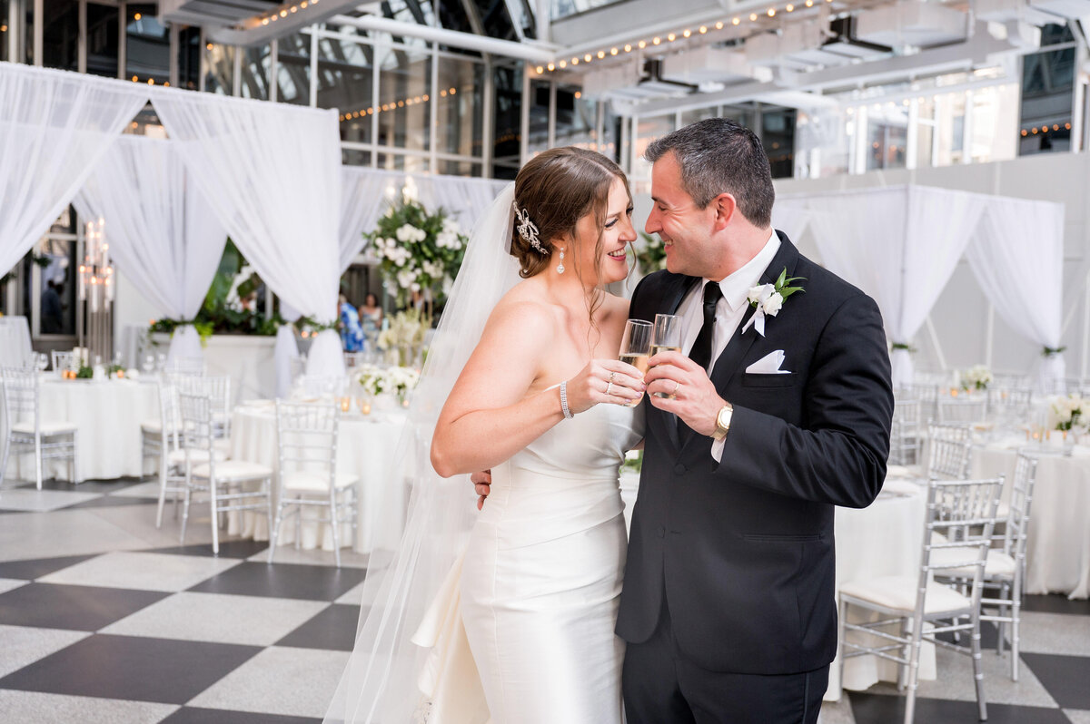 a couple cheers to each other on their pittsburgh wedding day surrounded by black and white wedding decor