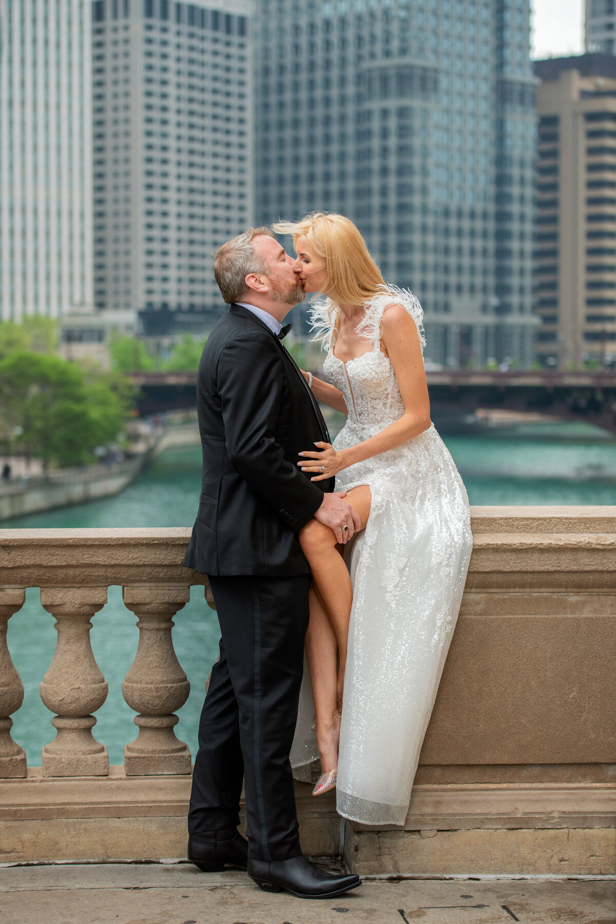 Groom is kissing his long legged bride in  Chicago riverwalk