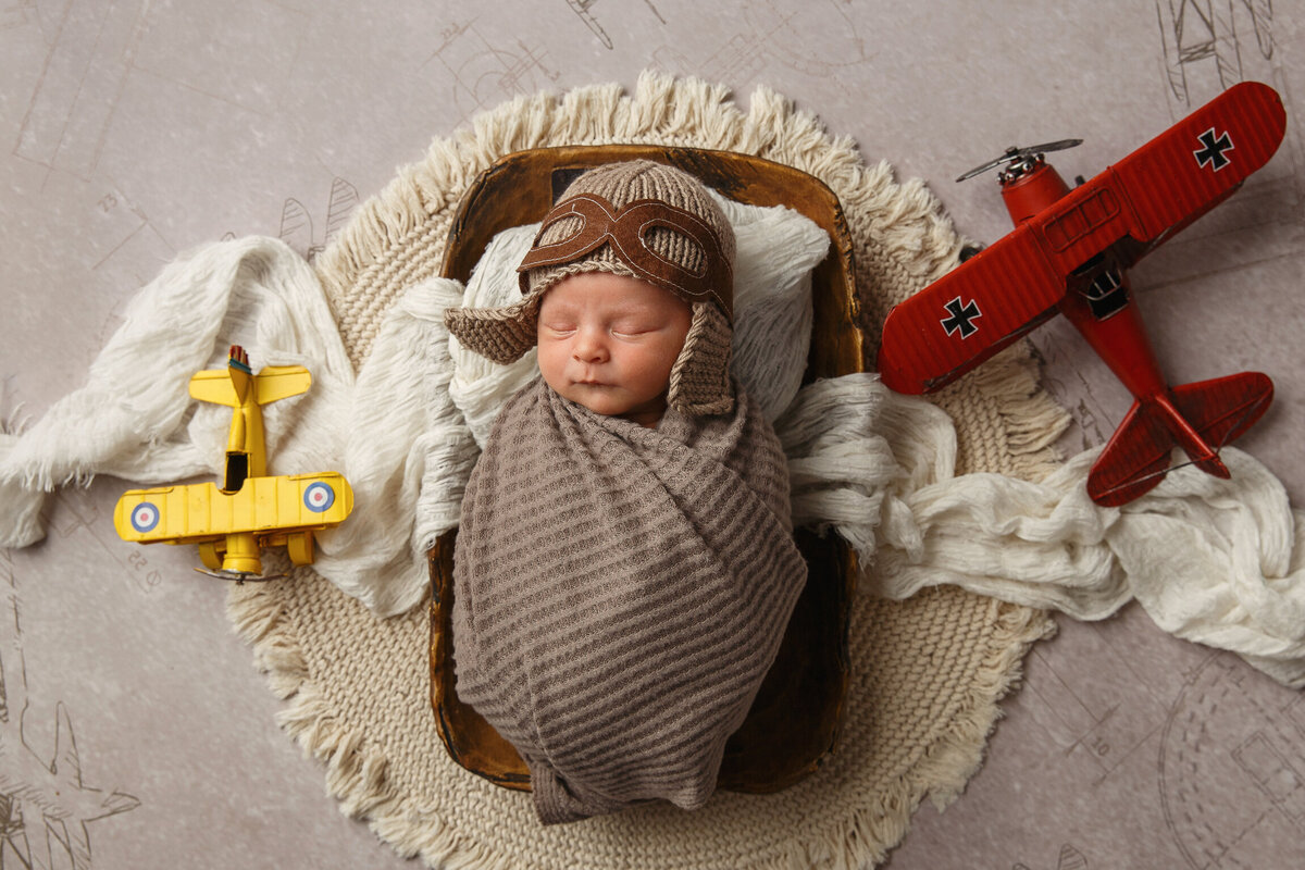 Newborn Portrait of a baby wrapped in a brown blanket with an aviator cap and glasses