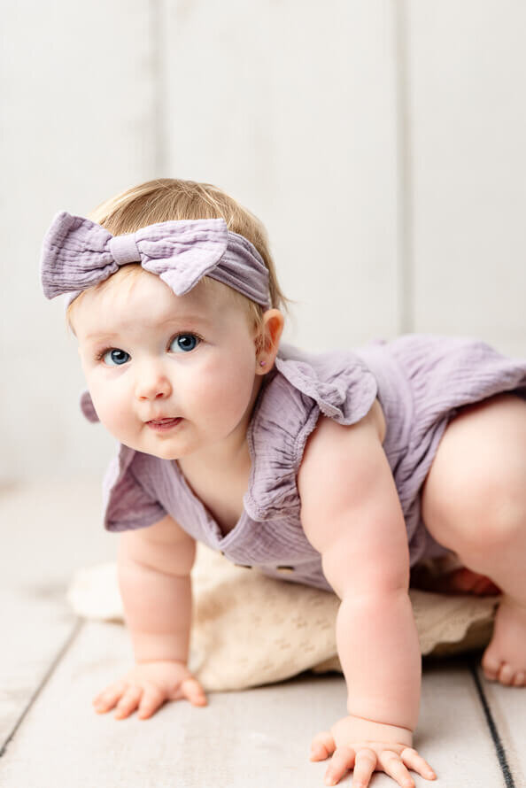 Baby in purple look at camera.