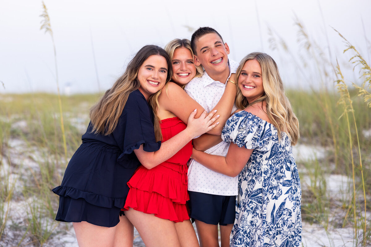 siblings standing wearing red, white and blue on Destin, Florida white sand beach.