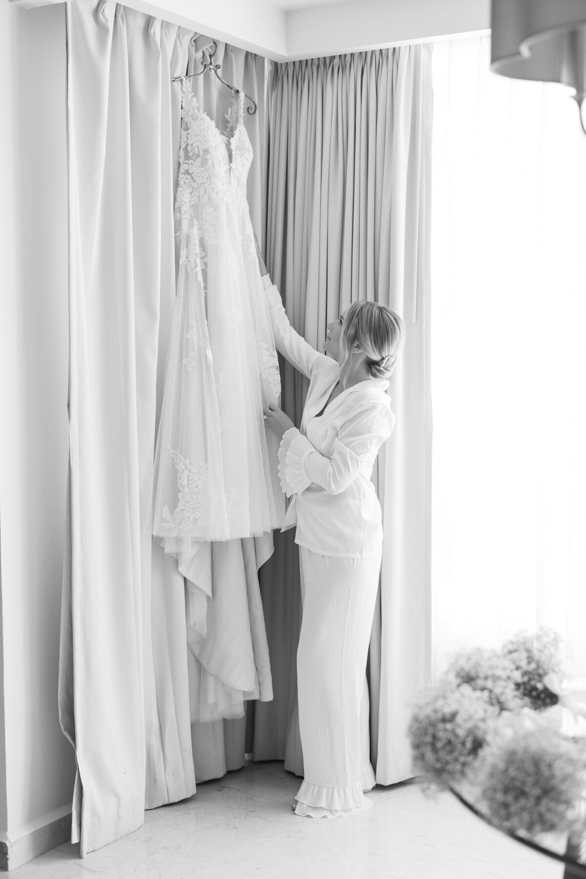 Bride reaching for her wedding dress in a Cancun suite, photographed by a Philly-based destination wedding photographer.