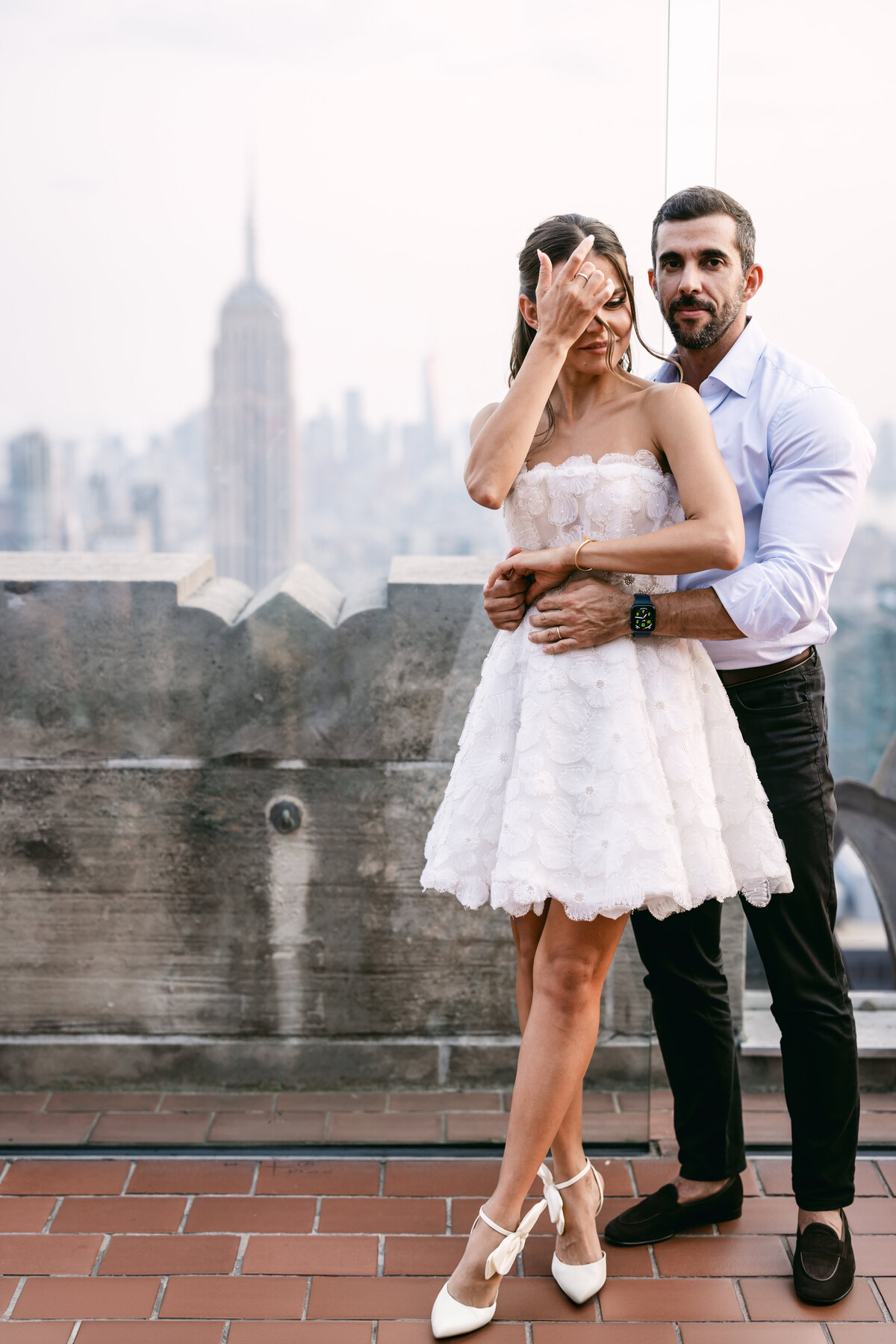 Stunning wedding photo of a couple posing on the Top of the Rock, with the panoramic views of New York City adding a touch of magic to their special day.