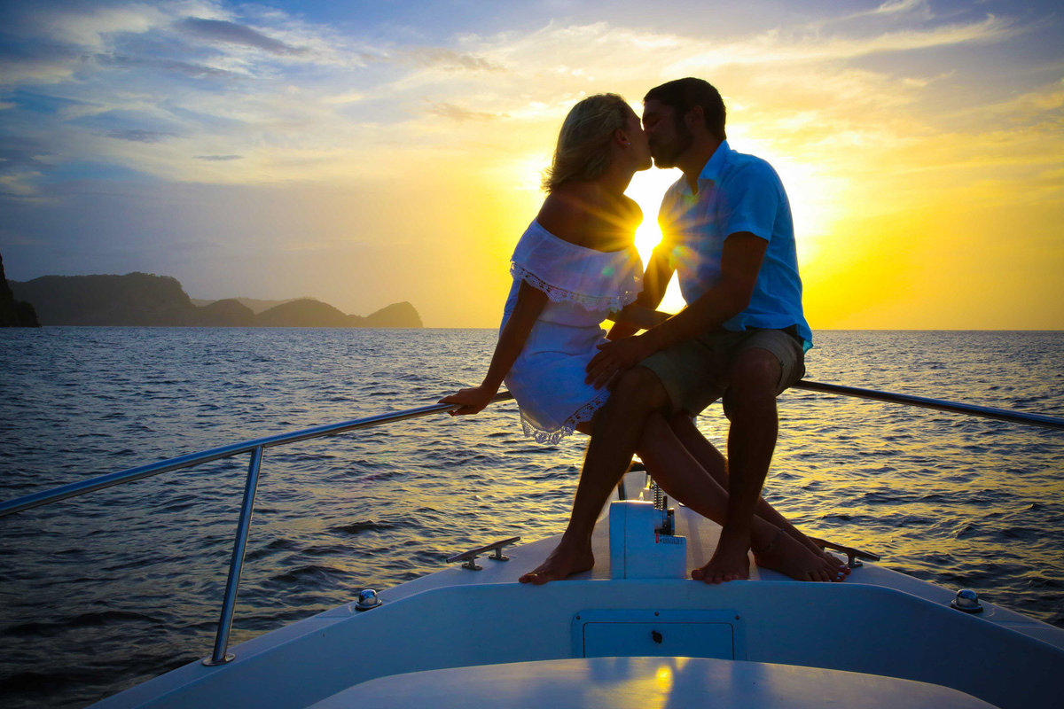 A couple kisses while sailing into the sunset on the bow of a yacht. Photo by Ross Photography, Trinidad, W.I..
