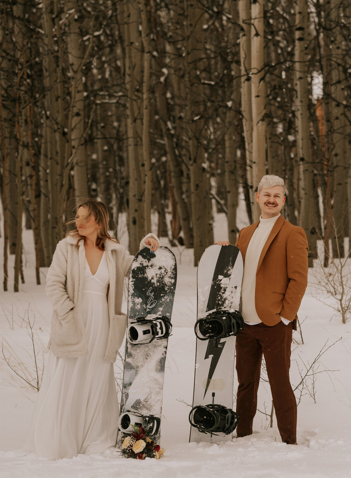 elopement couple hold their snowboards during their ceremony on a winter day in Bend, Oregon