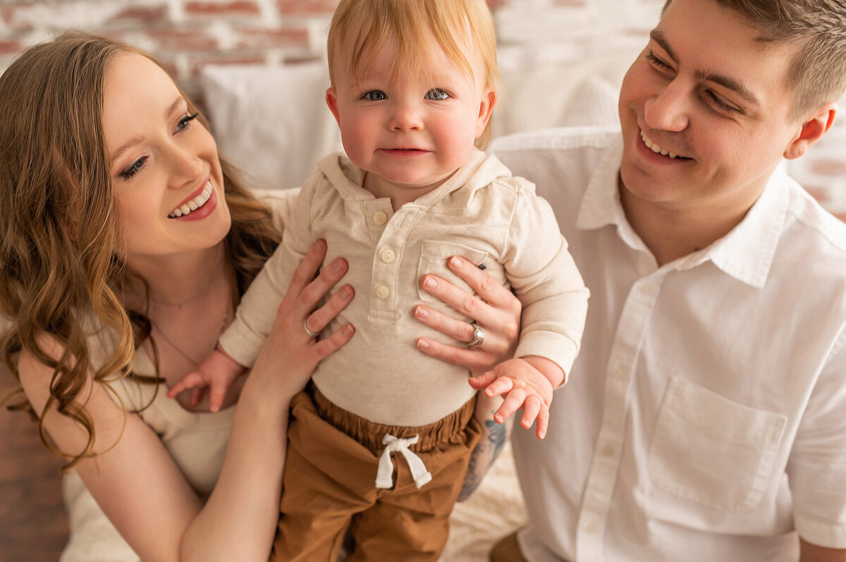 Mom and dad pose with their toddler son for a family portrait in our bright and airy Waukesha studio.
