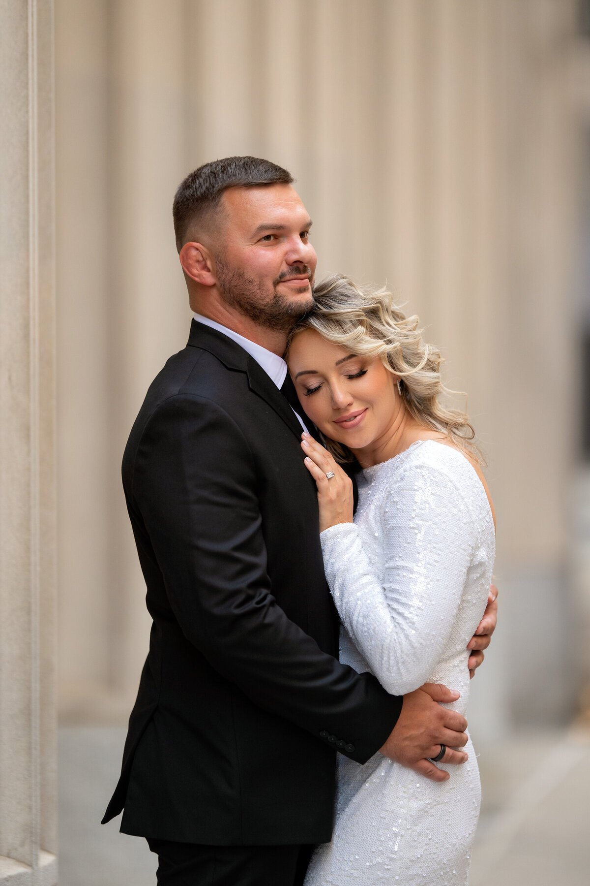 Bride with eyes closed resting her head against her husbands chest