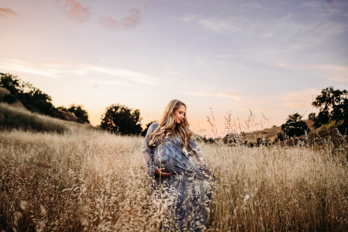 Pregnant mom in grass holding maternity dress