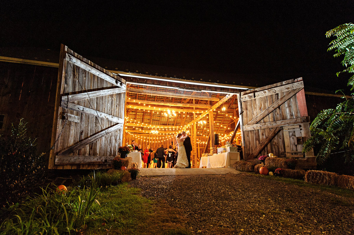 A bride and groom kiss at the entrance of their rustic barn wedding venue.