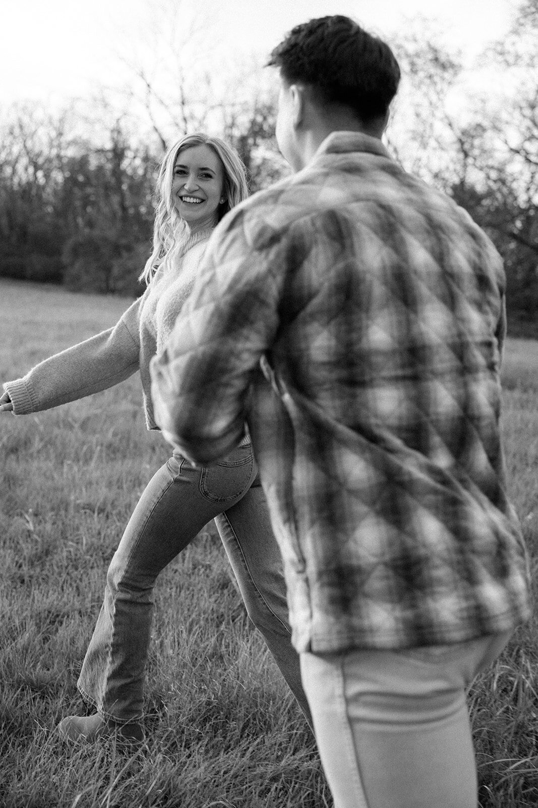 Couple locks eyes and holds hands while walking through farmland. 
