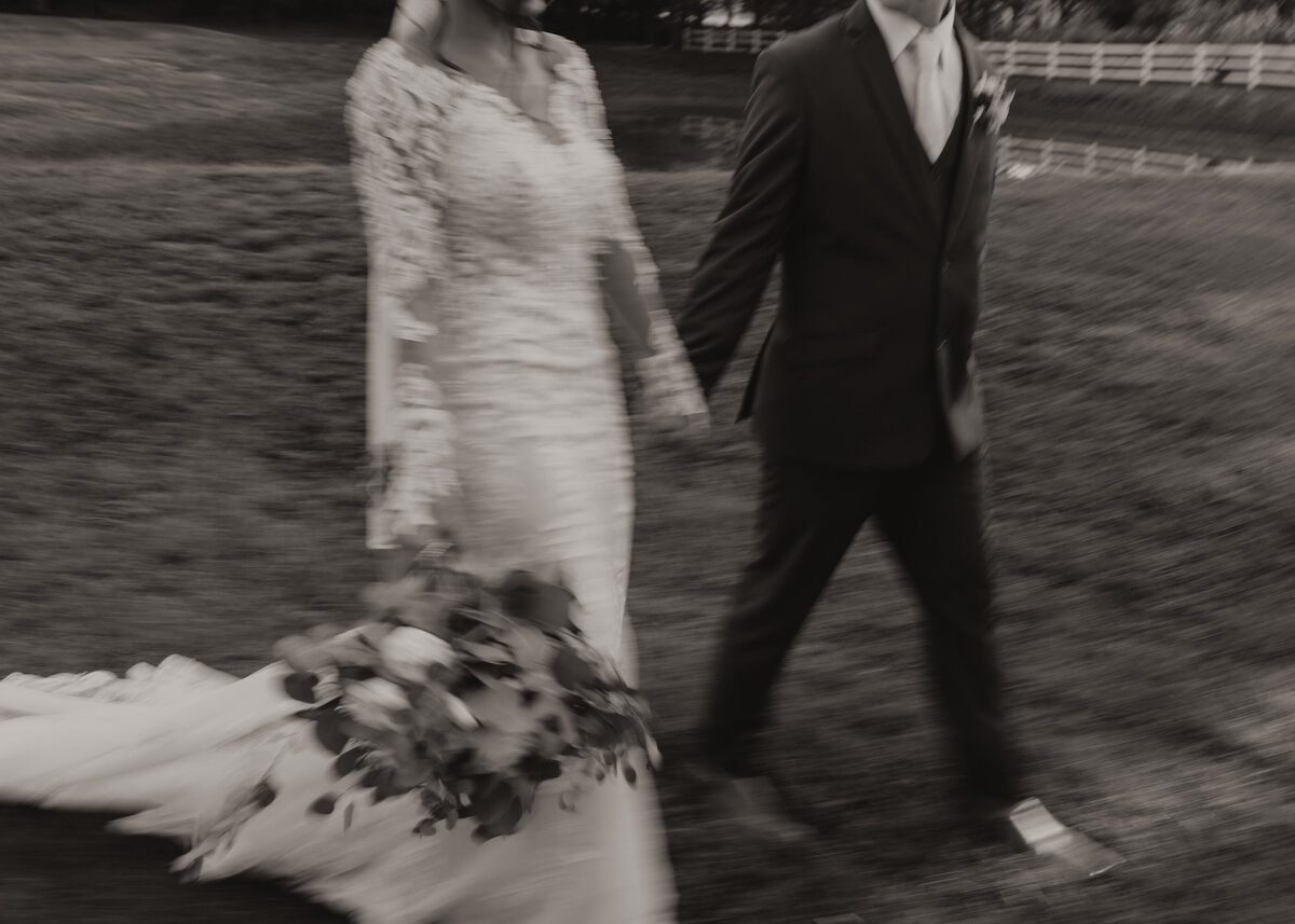 close up blurry shot of bride and groom walking and holding hands