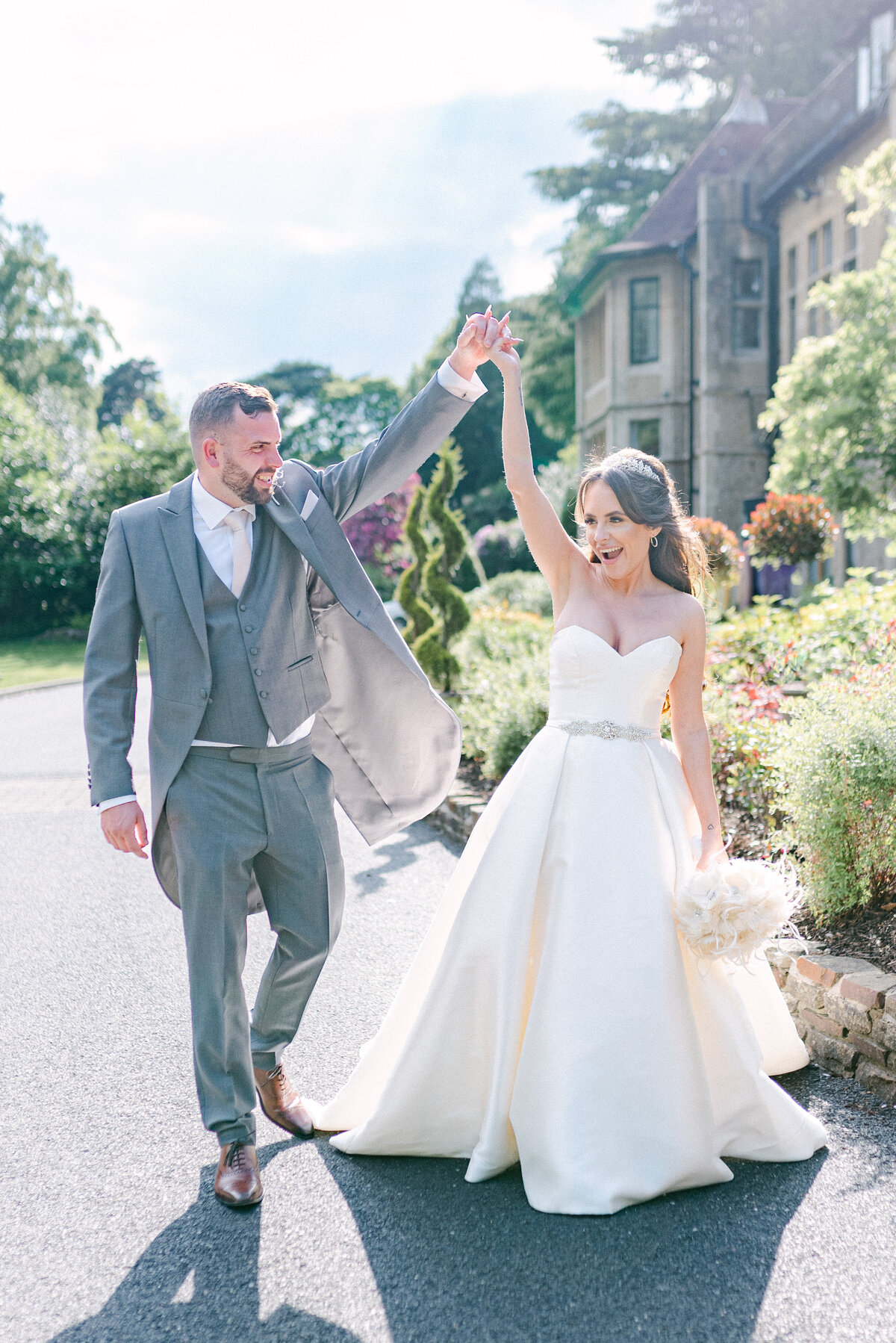 Bride and Groom walking together outside a surrey wedding venue hands in the air celebrating