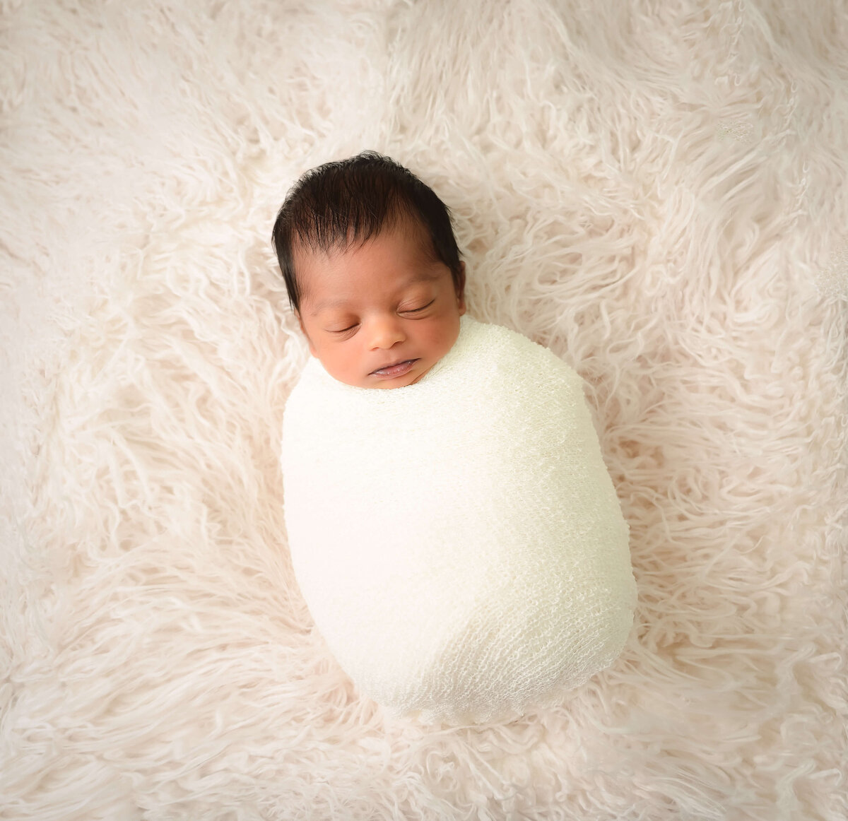 Dru drifted off to sleep on a fur blanket, wrapped in cream colors during this in home newborn photo session by E. Benecki Photography