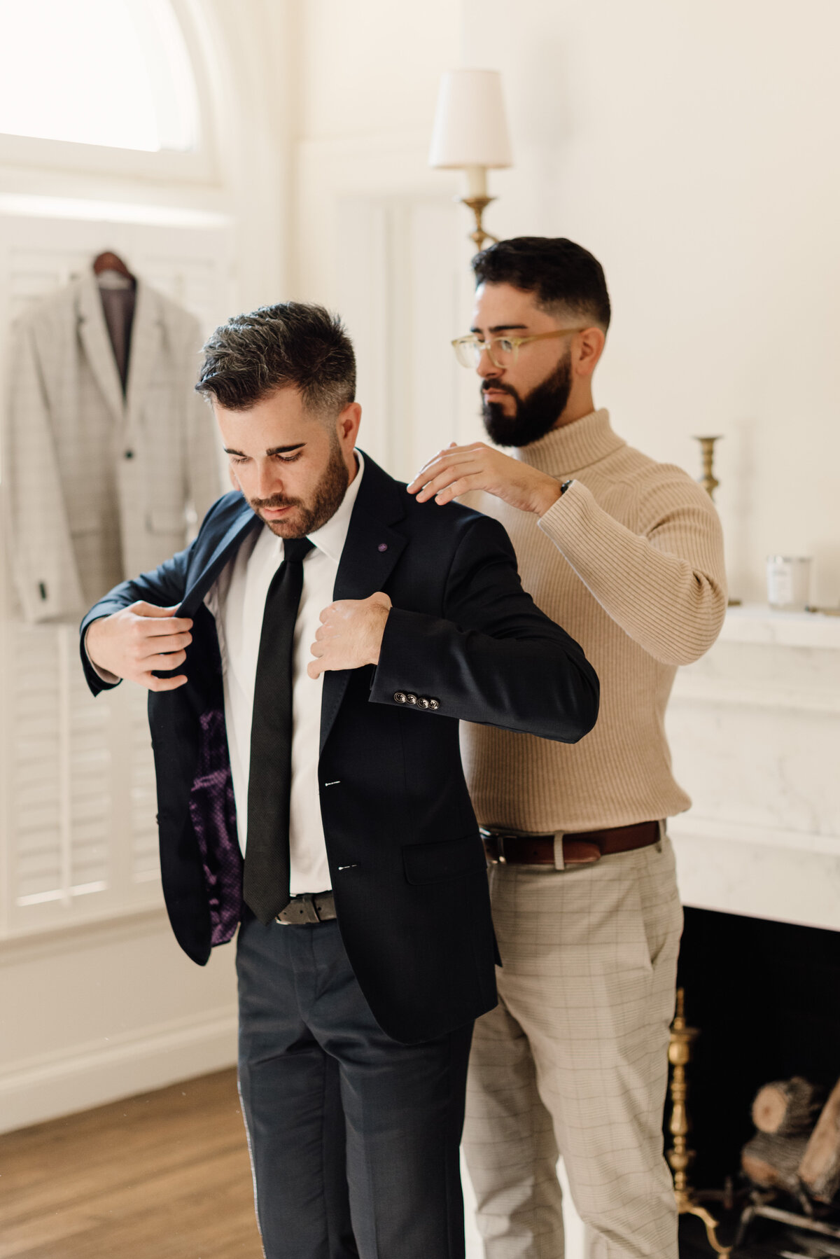 groomsmen helping groom with jacket on wedding day
