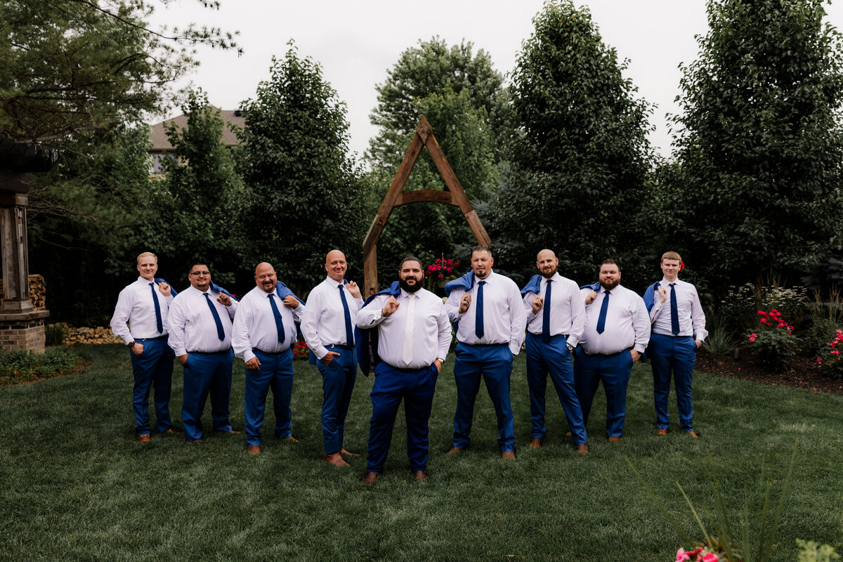 The groom and groomsmen hold their jackets over their shoulder.