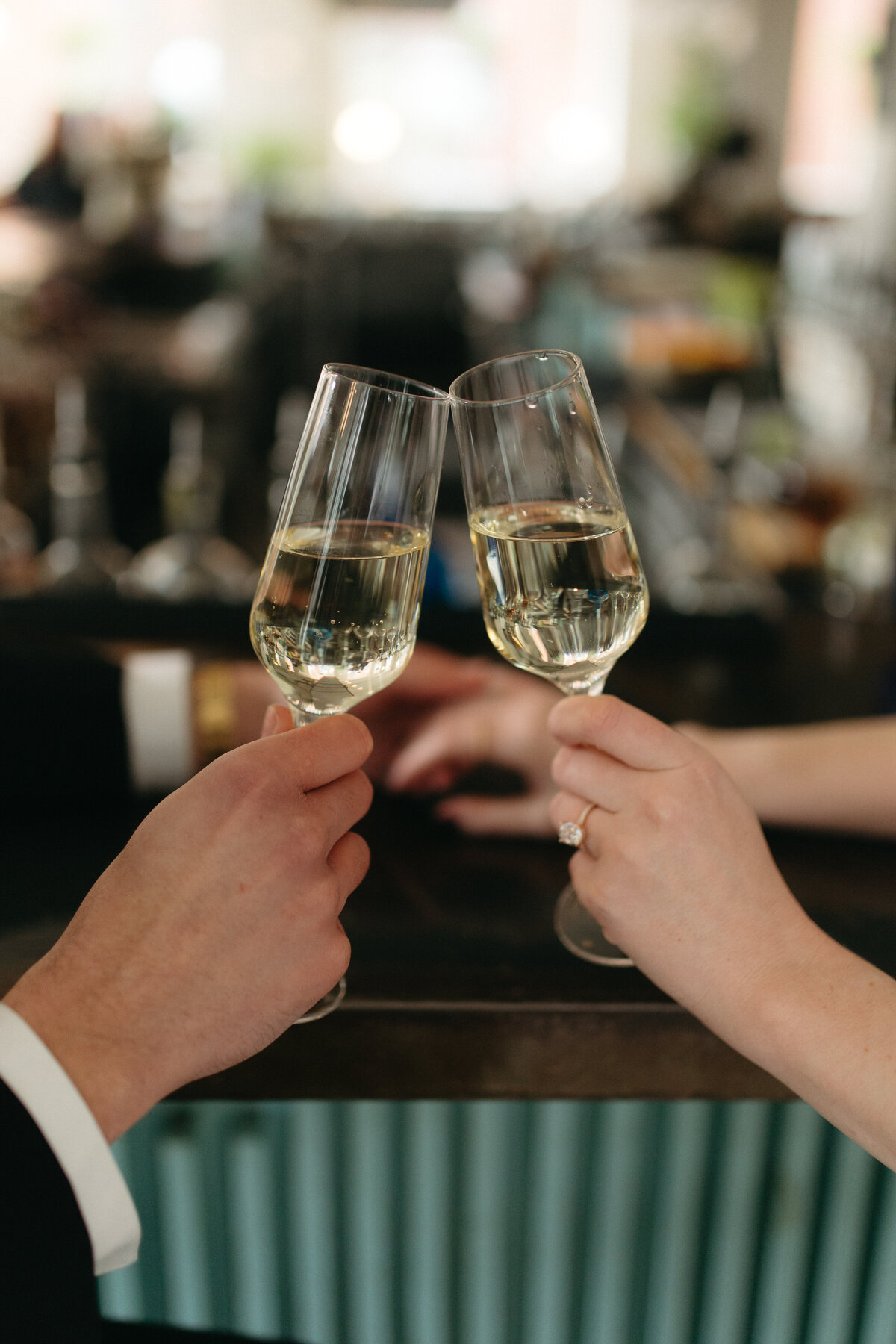 A couple toasting to their engagement while they sit at a Lancaster bar. They are drinking champagne. 