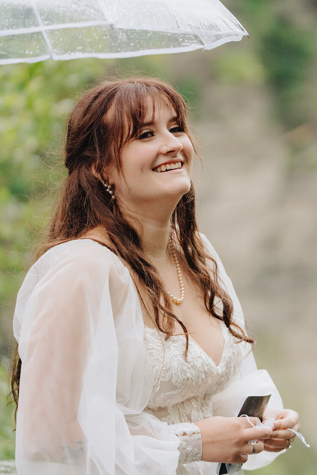Bride looking happy with umbrella held above her