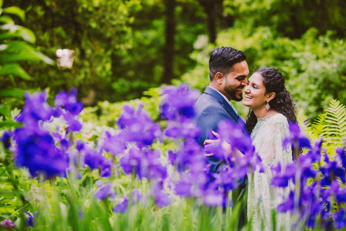 A couple sharing a moment in front of purple flowers at the shakespeare garden in central park nyc during their engagement session