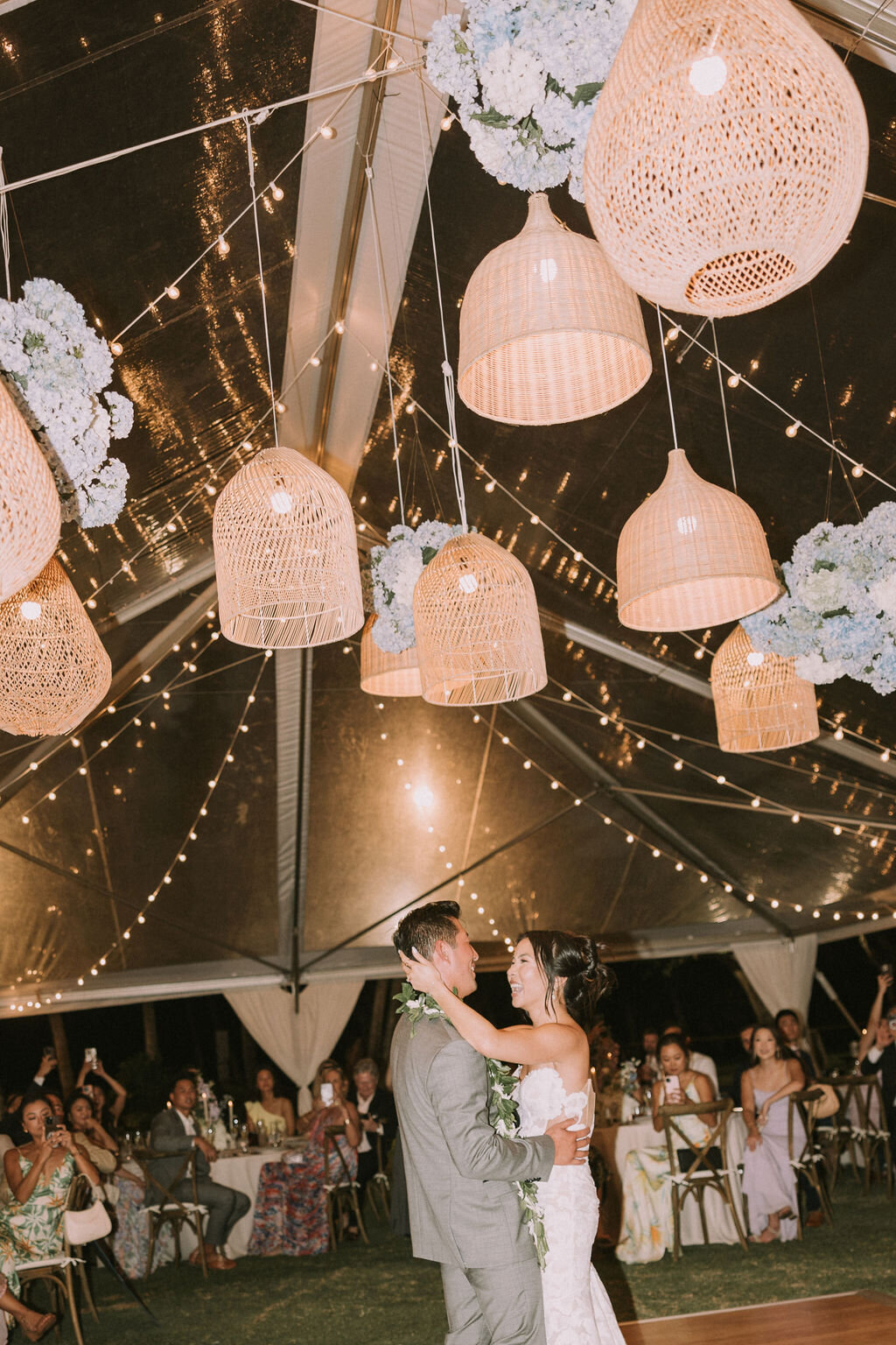 bride and groom filmy photo of first dance under lantern ceiling installation with gusts watching