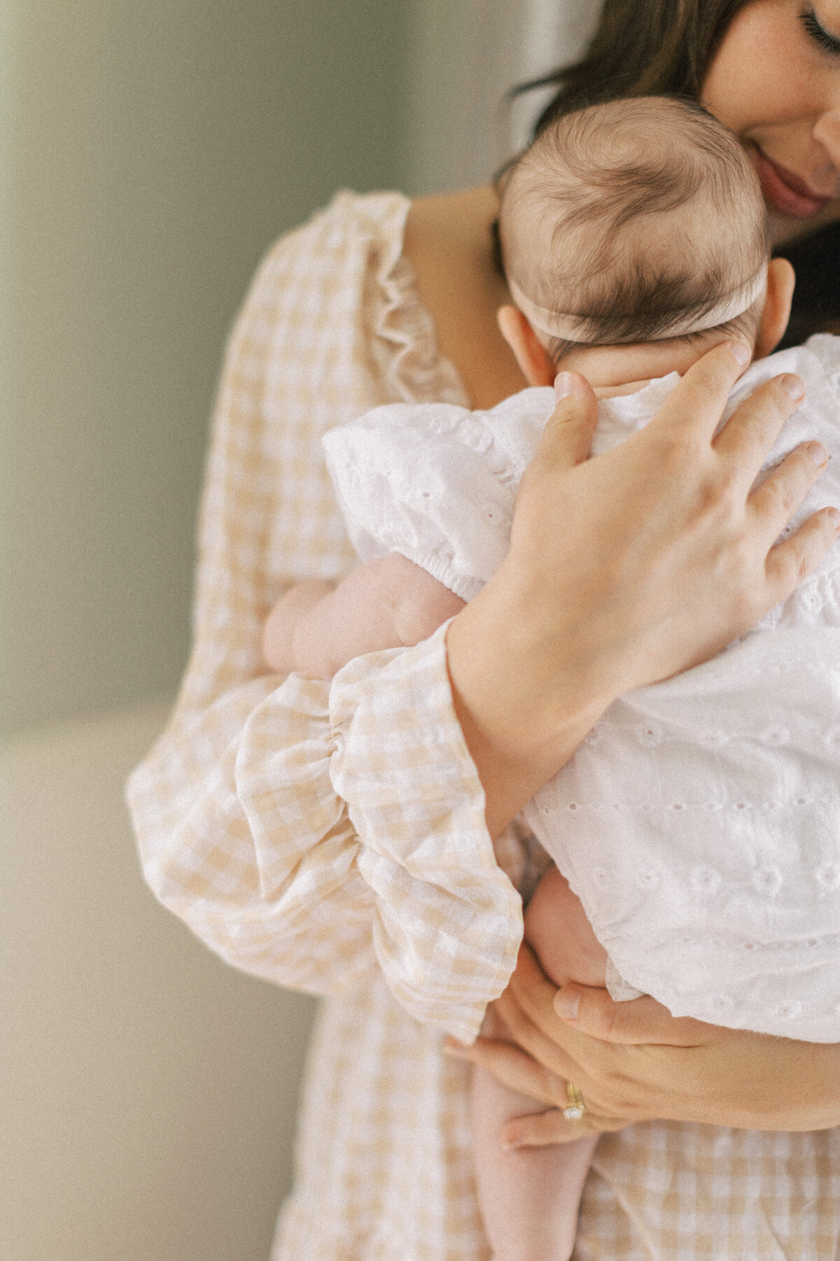 young mom holds infant close to chest for in home newborn photos