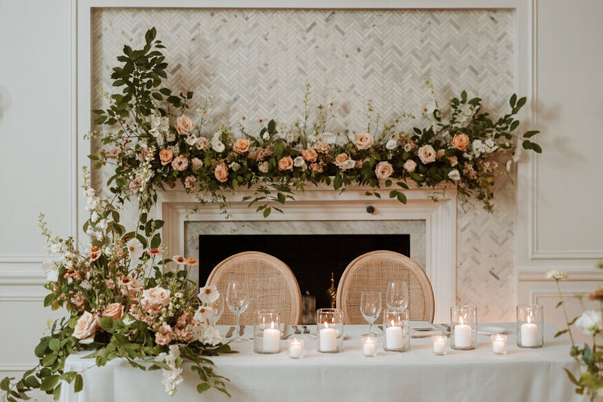 Lush sweetheart flowers on a table and fireplace at an Atwater Club wedding reception.