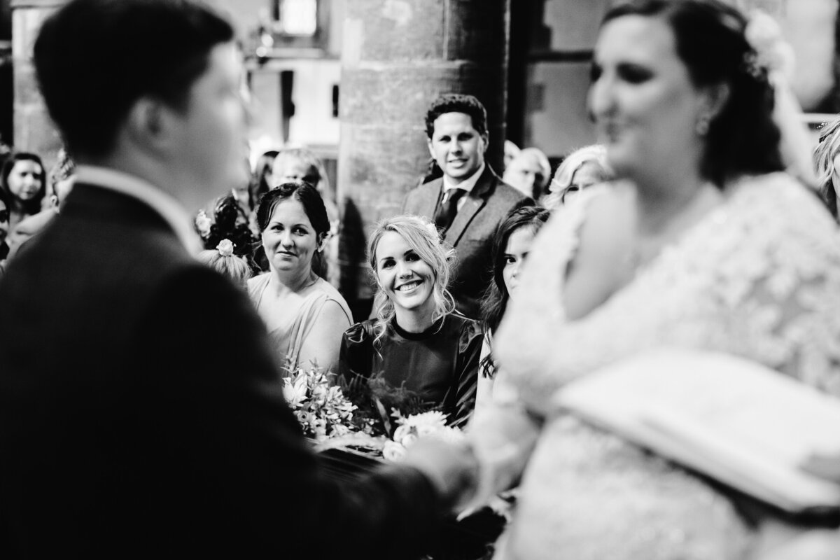 Black and White photo showing wedding guest smiling at couple