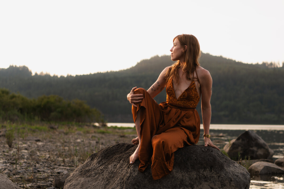 mentor, healer, guide sitting on river rock gazing at the horizon