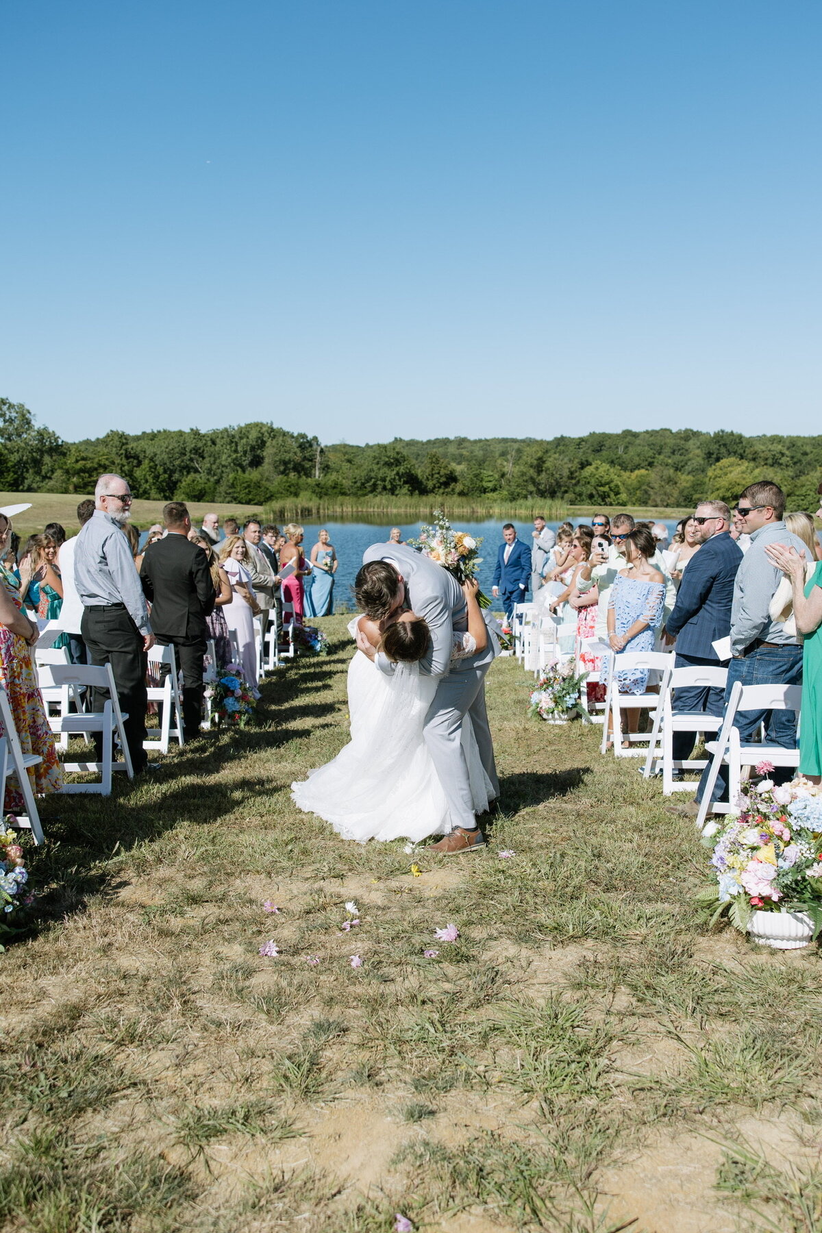 Bride and groom kiss exiting outdoor ceremony at Willstone Acres wedding venue