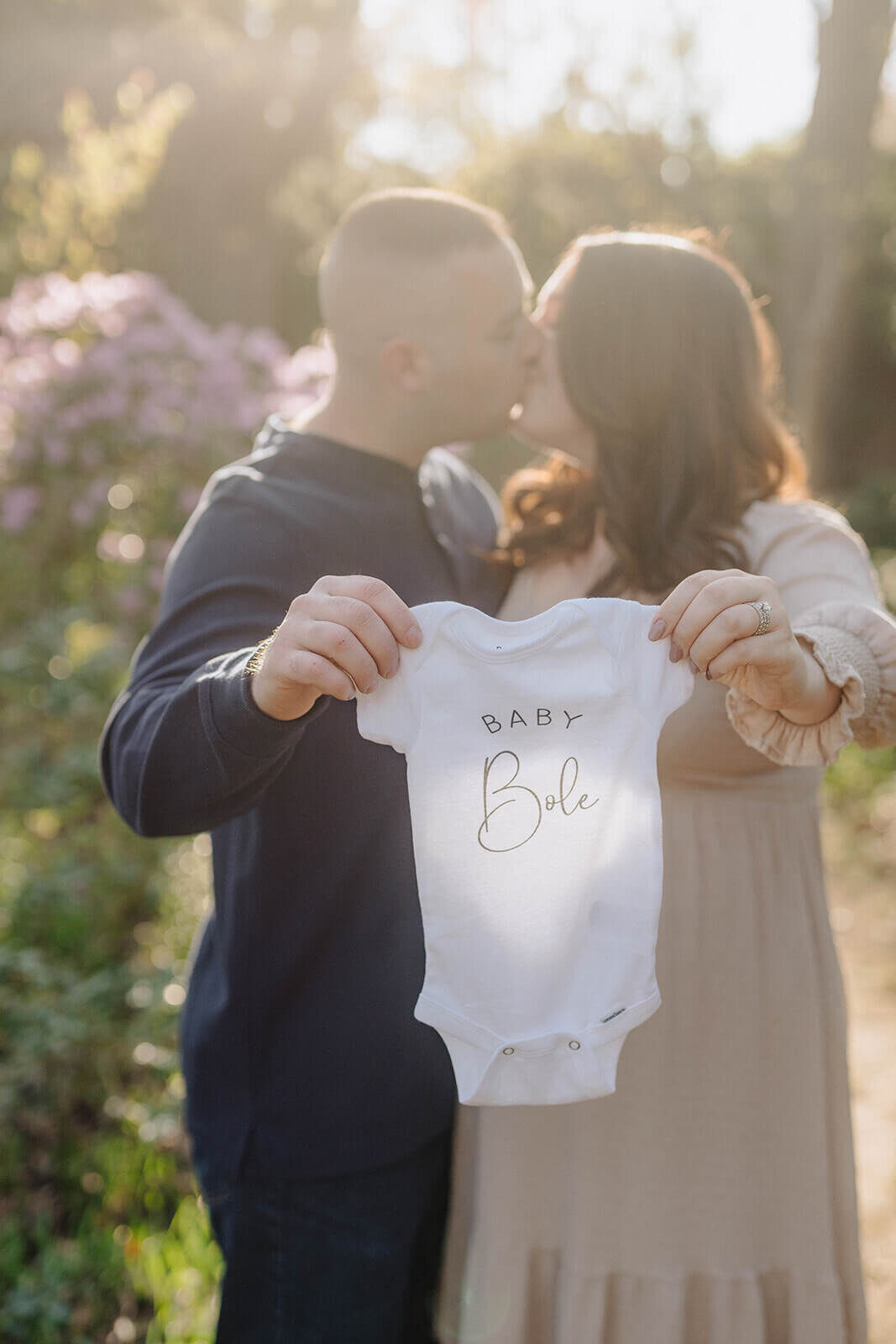 Couple holding onesie up at  Finger Lakes Maternity session