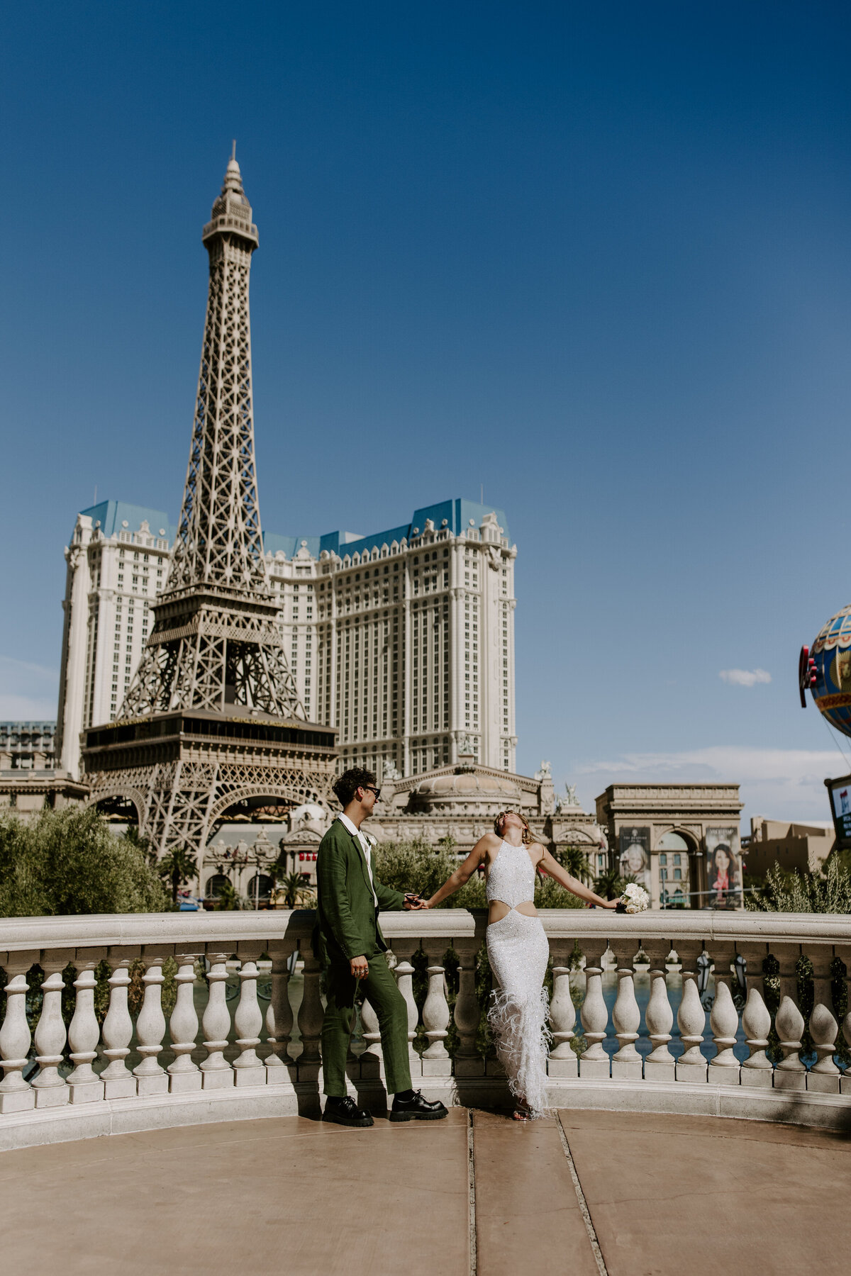 A couple poses on The Strip with the Paris Hotel behind them.