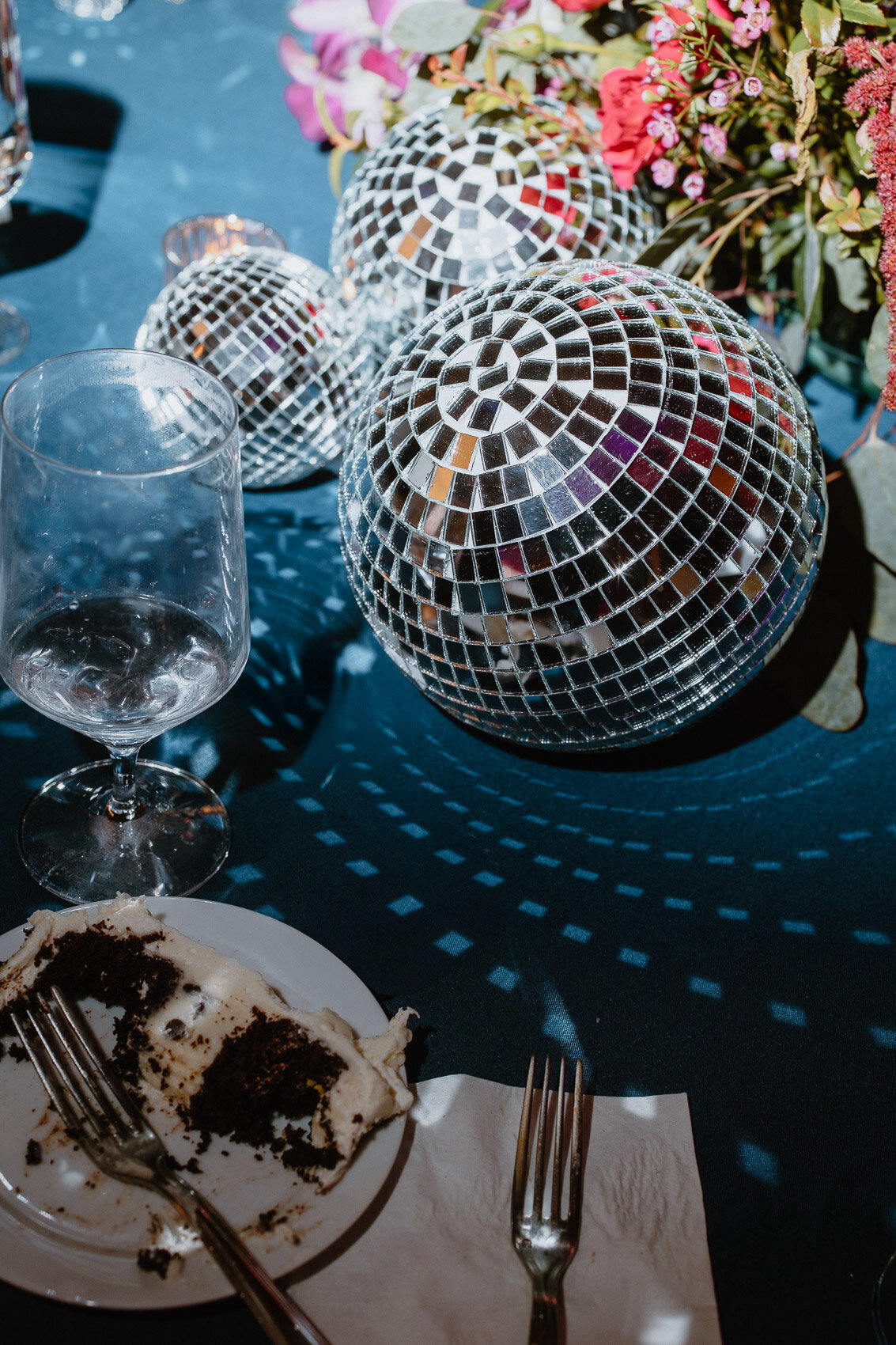A late-night flatlay with a disco ball and a slice of wedding cake. Fine art wedding photography.