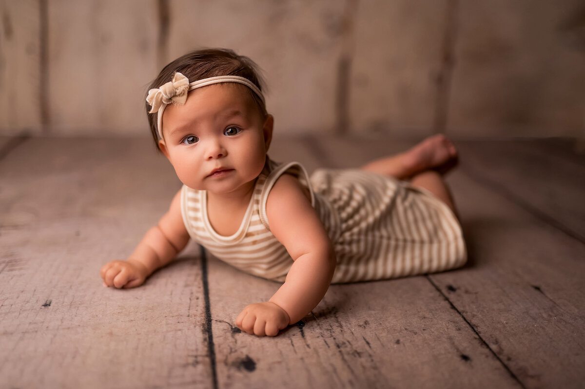 A baby girl lays on her belly on the floor of our Waukesha WI portrait studio.