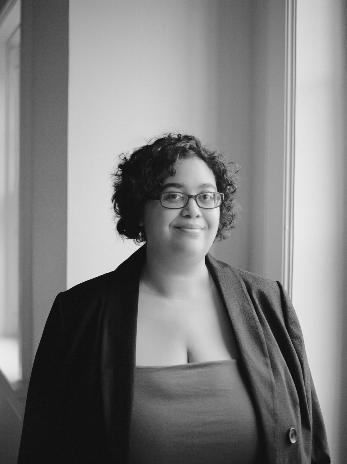 woman with curly hair, glasses, blazer, headshot for web designer brand photoshoot