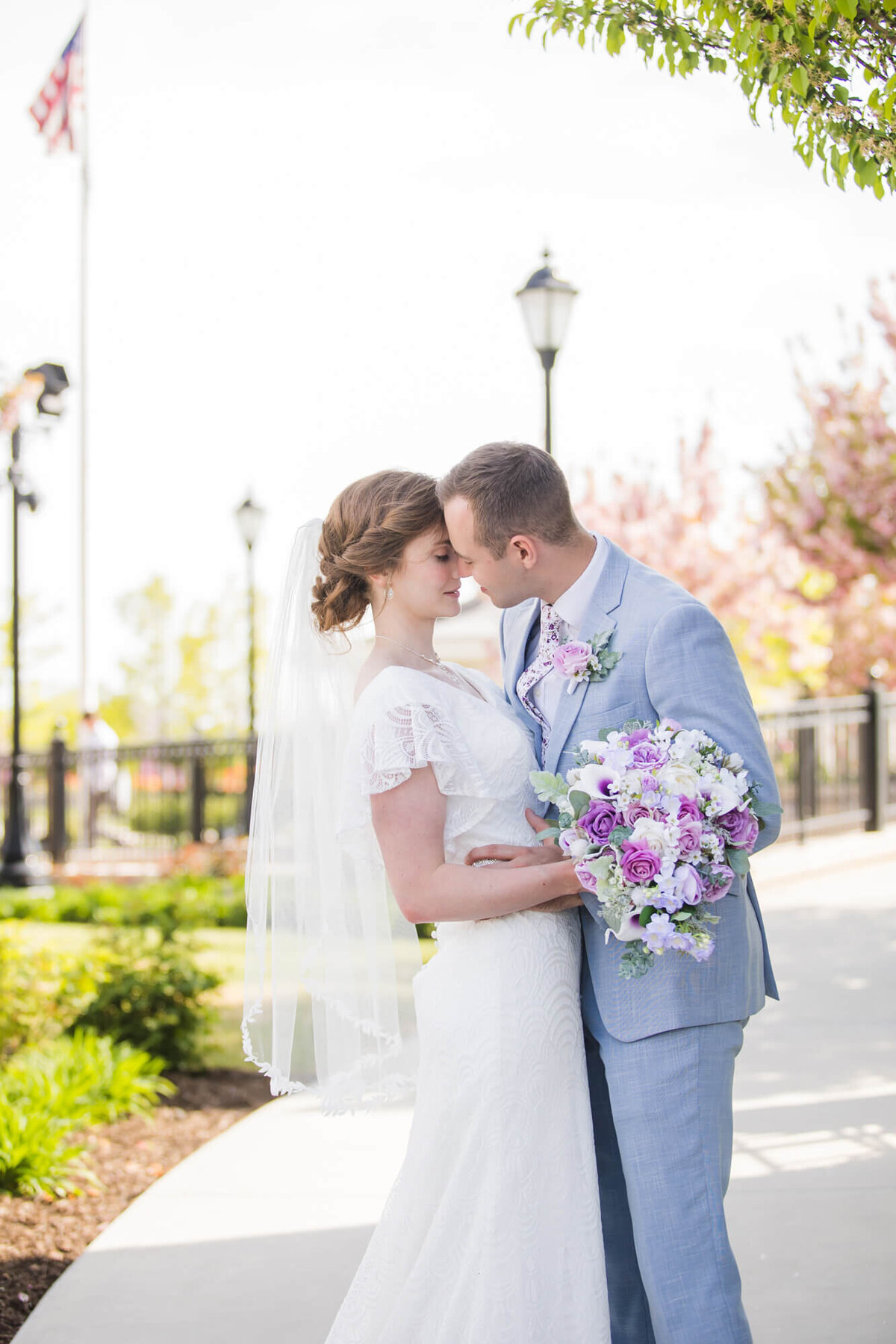 bride and groom kissing on a sidewalk