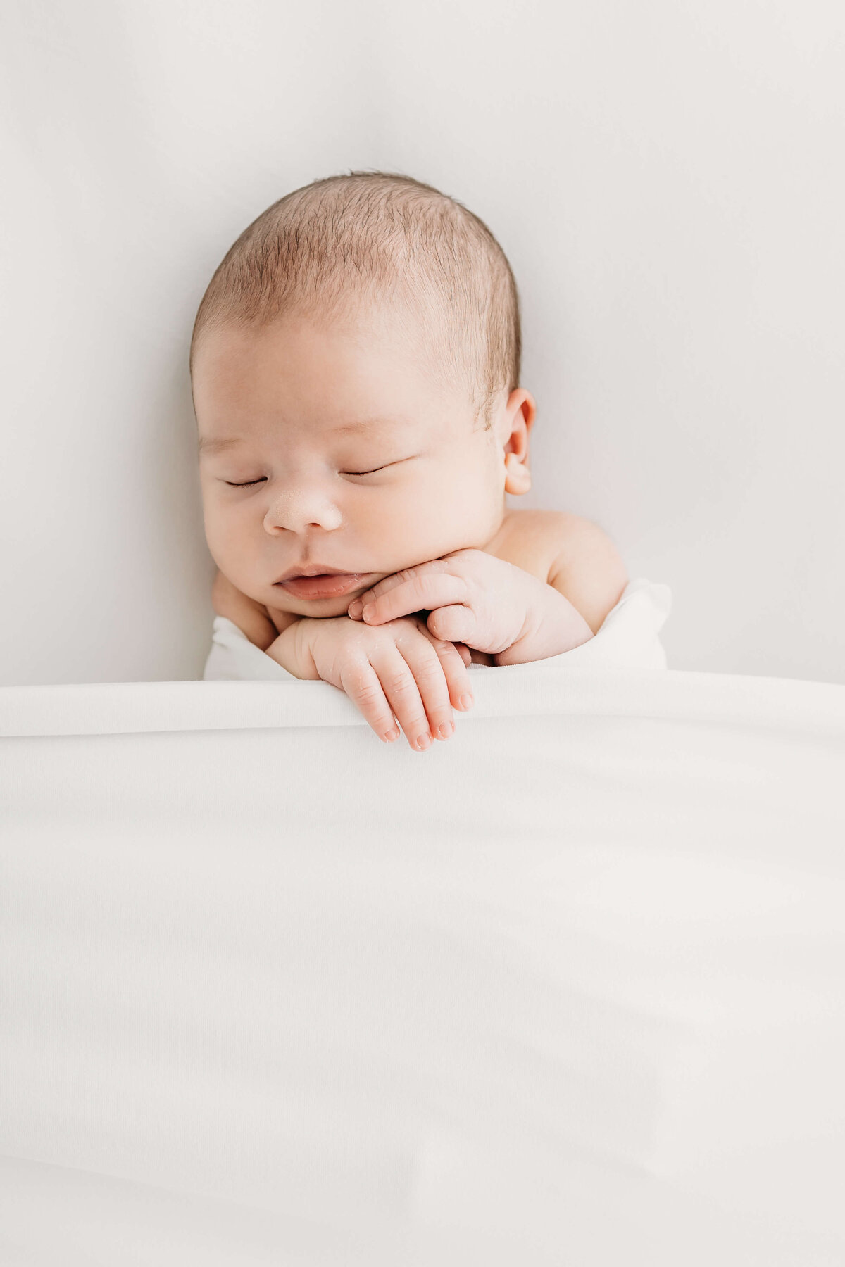 Tiny baby asleep in all white background by Luci Levon Photography