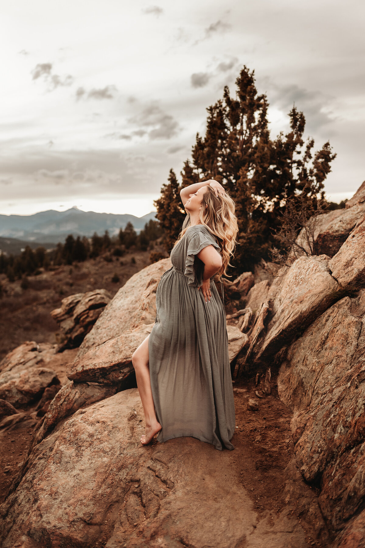 pregnant woman on mountain standing with foot out and hand in hair